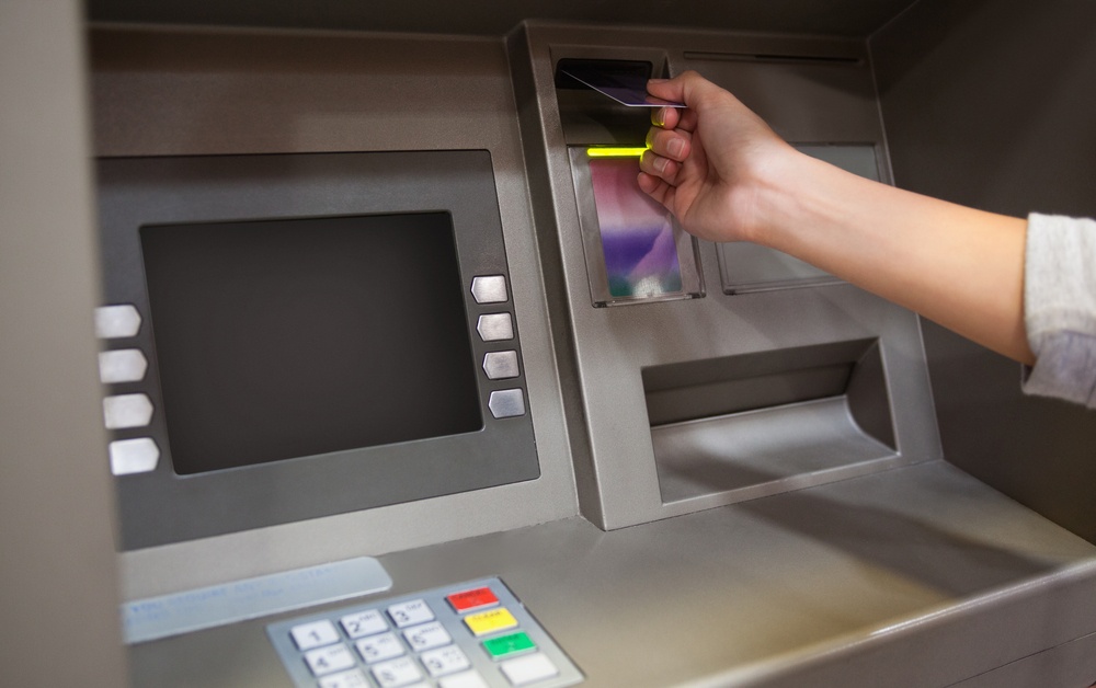 Hand inserting a credit card in an ATM